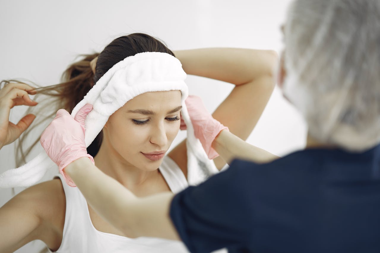A woman in a spa getting a facial treatment with assistance from a professional.